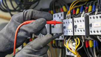 Elektrotechniker, der digitale Multimeter-Messgeräte verwendet, um die elektrische Stromspannung am Leistungsschalter in der Hauptstromverteilungsplatine zu überprüfen