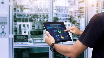 Intelligentes Branchensteuerungskonzept. Hände, die Tablet auf unscharfer Automatisierungsmaschine als Hintergrund halten. | © panuwat - AdobeStock