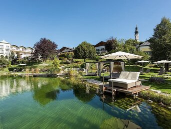 Wellness-Liege auf einem Steg am See im Garten mit Hotel im Hintergrund. | © Hotel Gmachl GmbH